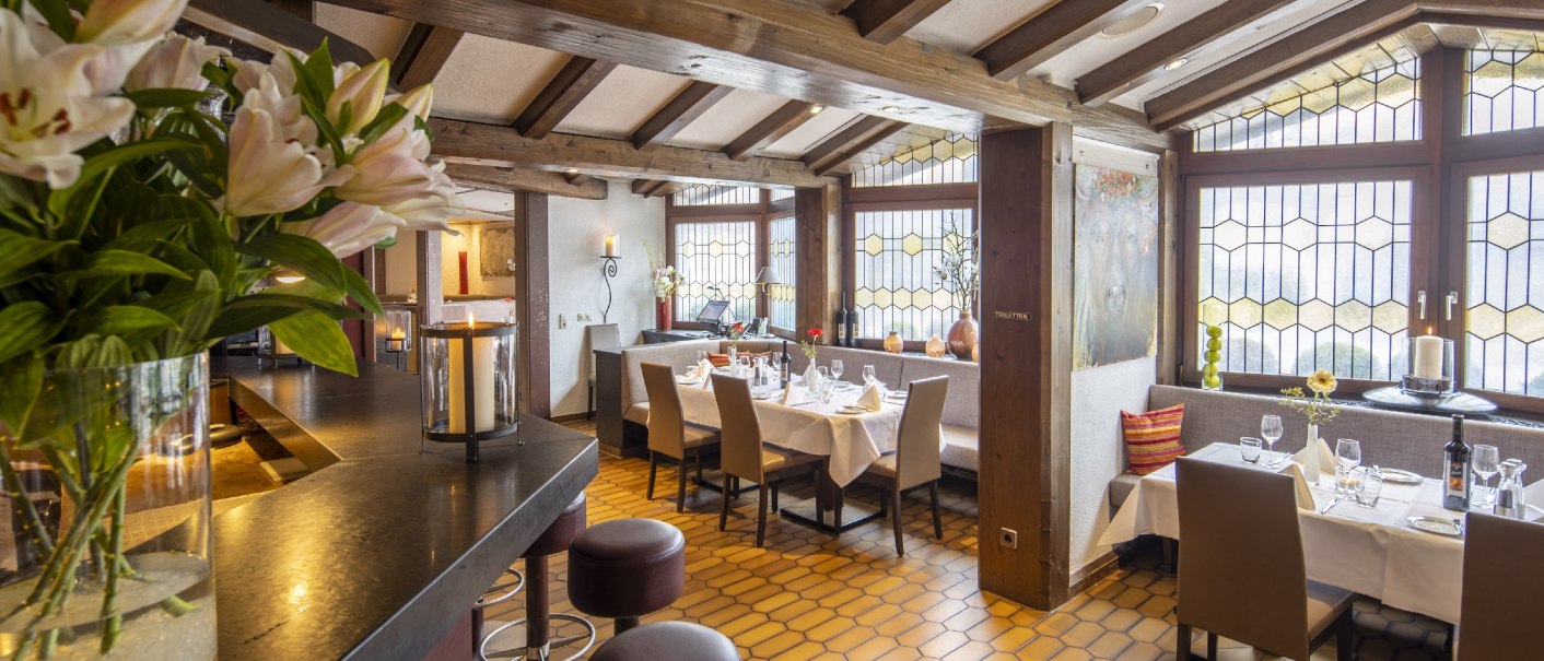 Elegantes Restaurant mit Holzbalken, gedeckten Tischen, gro&szlig;en Fenstern und Blumenarrangement., &copy; Hotel Gloria