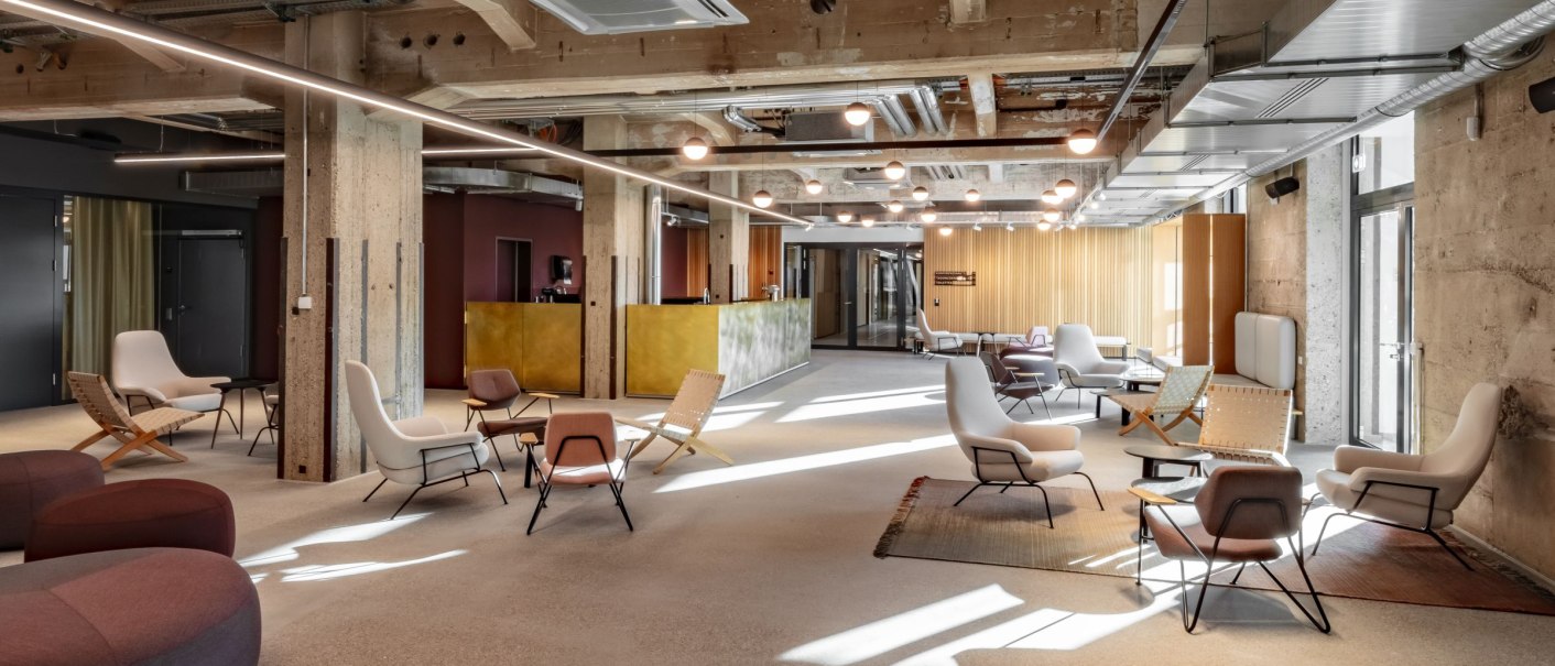 A modern foyer with an industrial design, bright seating and a reception counter. Visible pipes and concrete walls lend an urban look., © Stefan Baraniecki