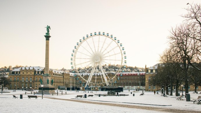 Wintery Schlossplatz in Stuttgart with snow-covered ground, a tall column and a large Ferris wheel in front of a castle in the background., © Stuttgart-Marketing GmbH, Sarah Schmid Wintery Schlossplatz in Stuttgart with snow-covered ground, a tall column and a large Ferris wheel in front of a castle in the background., © Stuttgart-Marketing GmbH, Sarah Schmid