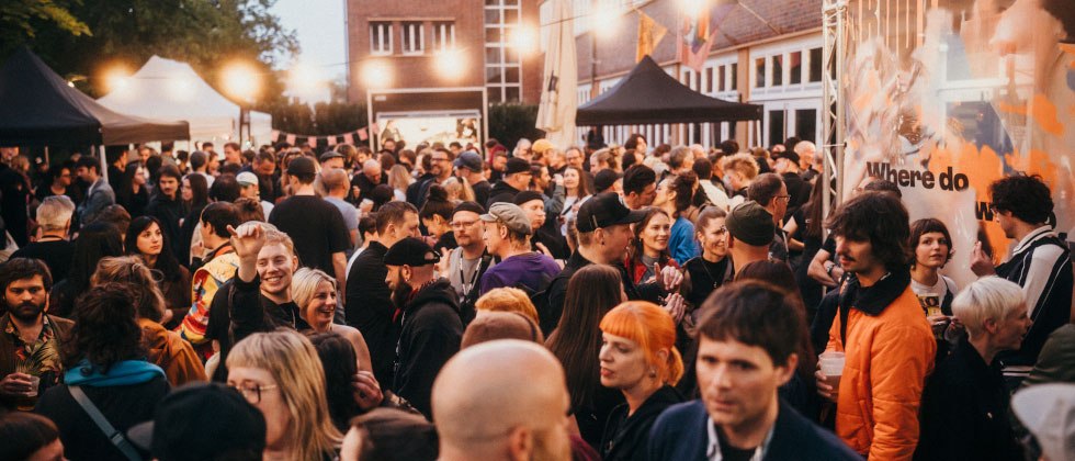 Large crowd at an outdoor event with festive lighting and various stands in the background., &copy; Ilkay Karakurt