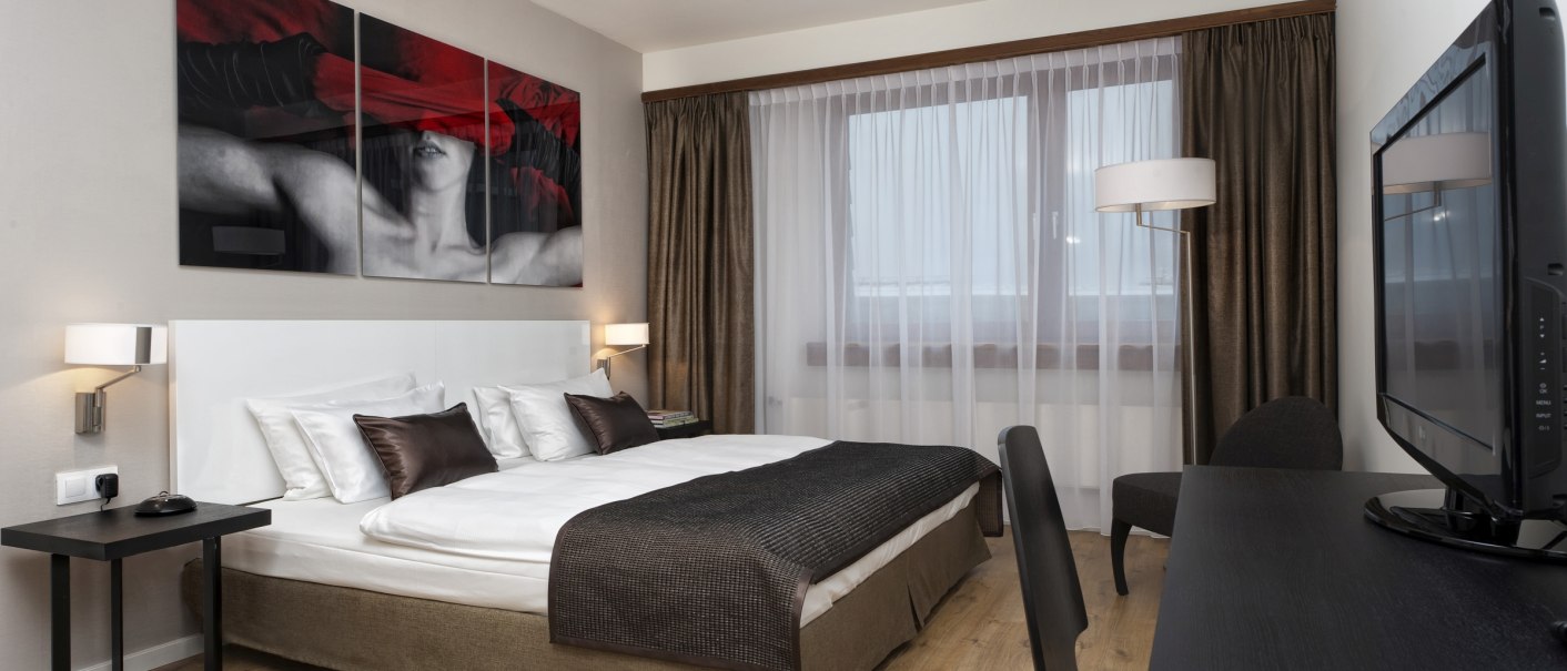 Modern double room with large bed, stylish artwork, desk and TV. Light-colored curtains and wooden floor create an inviting atmosphere., © Wyndham Stuttgart Airport Messe Modern double room with large bed, stylish artwork, desk and TV. Light-colored curtains and wooden floor create an inviting atmosphere., © Wyndham Stuttgart Airport Messe
