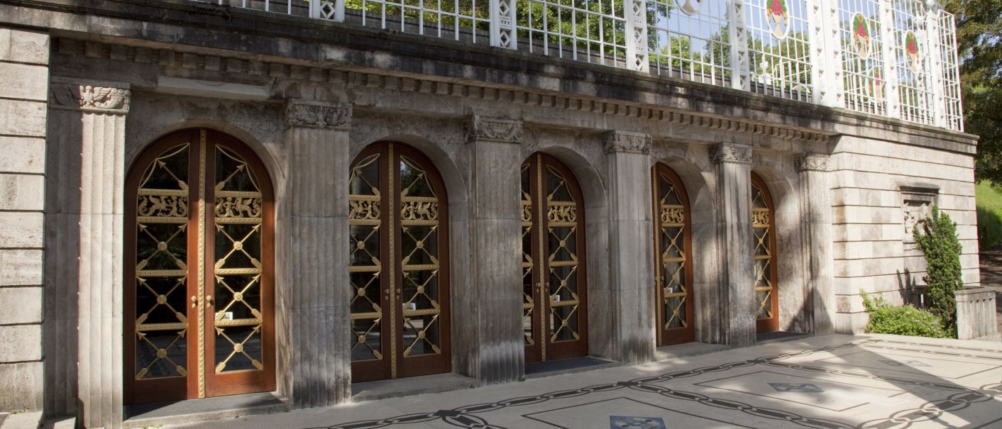 A terrace with a marble floor, ornate wooden doors, and a decorative fence. The sun casts shadows on the floor., &copy; csusannmeissner