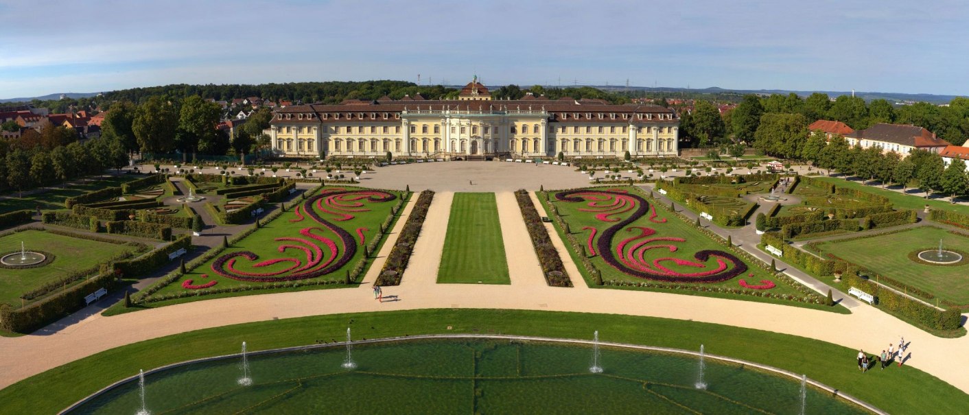 Aerial view of Ludwigsburg Residential Palace, surrounded by symmetrical gardens and fountains, with green lawns and flowering beds., © Tourismus & Events Ludwigsburg Aerial view of Ludwigsburg Residential Palace, surrounded by symmetrical gardens and fountains, with green lawns and flowering beds., © Tourismus & Events Ludwigsburg