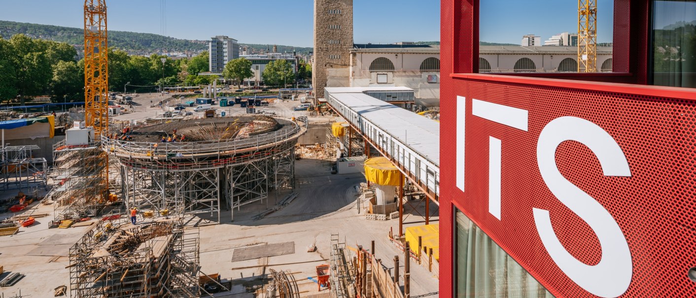 Baustelle in Stuttgart mit einem Turm und einem roten Gebäude im Vordergrund. Ein Kran und Bauarbeiten sind sichtbar, blauer Himmel im Hintergrund., © ThomasNiedermüller