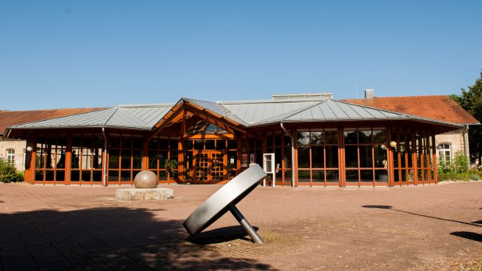 Die Melchior Festhalle in Neckartenzlingen mit gro&szlig;em Eingangsbereich aus Glas und Holz. Eine moderne Skulptur steht im Vordergrund auf dem Platz., &copy; davidhaas_gf