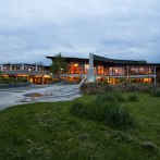 The Waiblingen community center at dusk, illuminated with large windows and surrounded by green spaces and sidewalks., © Peter Oppenländer