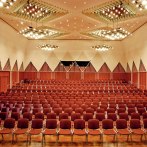 Large conference room with red chairs, modern lighting and geometric wall patterns in the Kronenzentrum Bietigheim-Bissingen., © Kronenzentrum Bietigheim-Bissingen