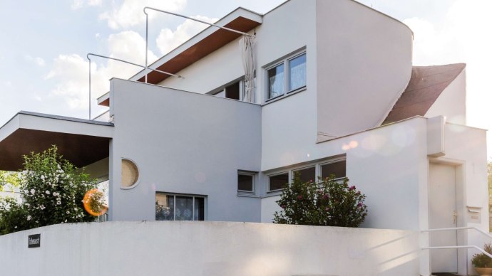 Modernes Gebäude der Weissenhofsiedlung von Hans Scharoun, mit klaren Linien und geometrischen Formen, umgeben von Pflanzen und hellem Himmel., © TMBW, Gregor Lengler