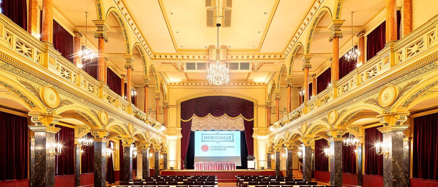 Magnificently decorated hall in the Ludwigsburg Music Hall with chandeliers, high ceilings and rows of tables and chairs., © Stauch