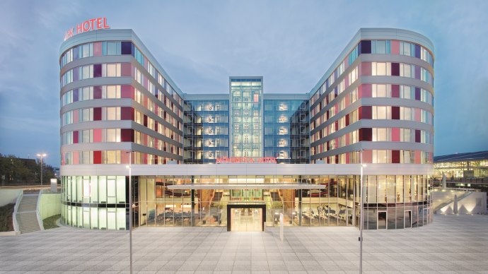 Moderne Fassade des Mövenpick Hotels Stuttgart Airport bei Dämmerung, mit beleuchteten Fenstern und einem großen Eingangsbereich., © Mövenpick Hotel Stuttgart Airport